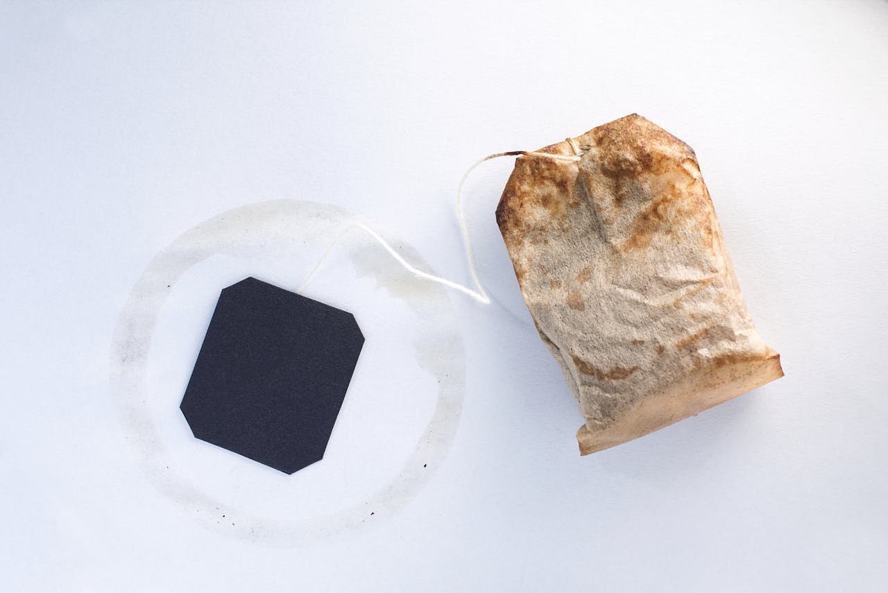 services-03 Close-up of a used tea bag with a black tag on a clean white background.