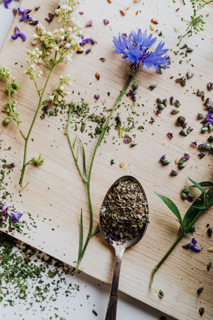 gallery-6 Fresh cornflower and herbs scattered on wooden board with spoon of dried herbs, ideal for organic themes.