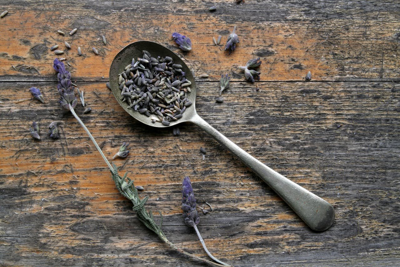 about-01 Close-up of lavender seeds on a vintage spoon on a wooden surface, rustic theme.