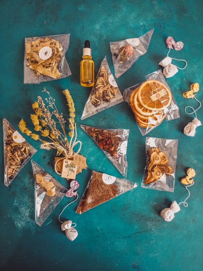 Colorful flat lay of herbal tea bags, dried oranges, and decorative elements on a teal background.